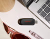 A SANDISK USB-C Flash Drive - 256 GB  in black with a red logo, styled on a white desk next to a laptop keyboard, sunglasses, and a pen.